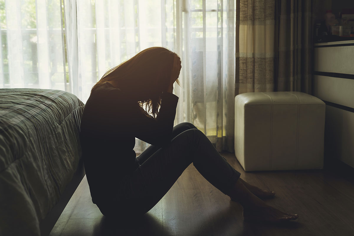 Mental Health- Helpful Tips for Coping With Depression woman sitting on the floor at the end of her bed trying to deal with her depression