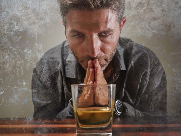 Ways to Know When to Seek Alcohol Treatment man looking at glass of alcohol and thinking about seeking out alcohol treatment