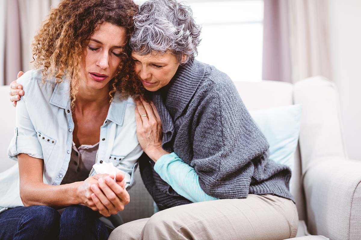Older mother hugging her adult daughter who is going through addiction
