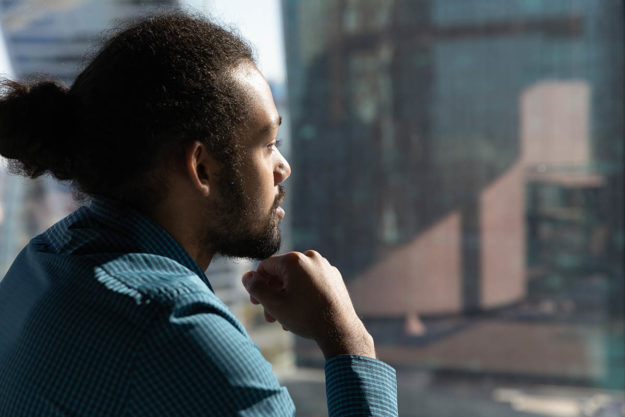 Man looking out window thinking about giving up alcohol